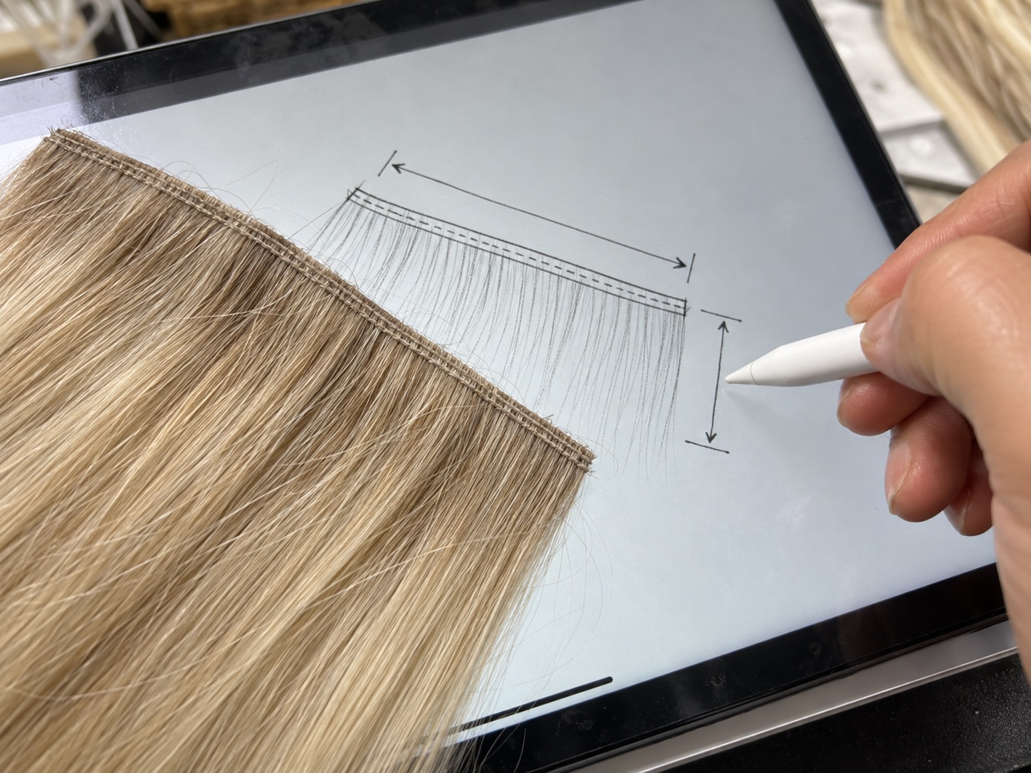Hair extension technician designing a custom weft specification on a tablet